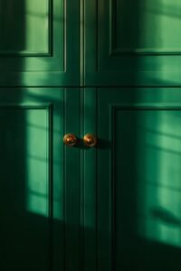 Emerald green kitchen cabinets with brass hardware and window light