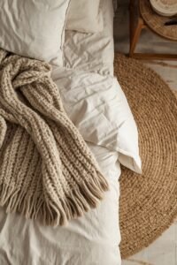 Cozy master bedroom makeover: neutral bed with chunky knit blanket and jute rug.